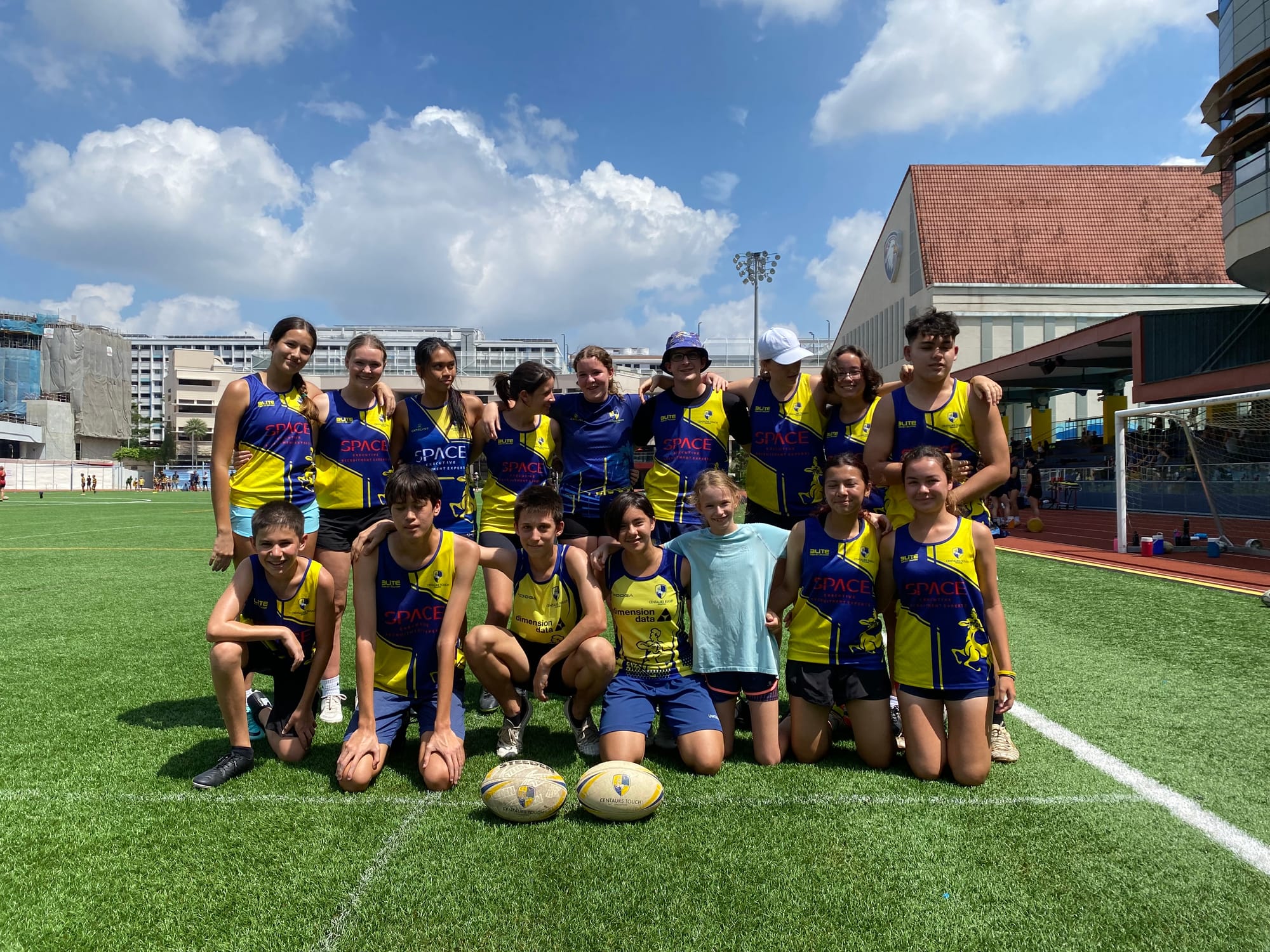 The Centaurs Touch squad, boys and girls in blue and yellow kit, together on the pitch with two match balls in front of them